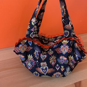 Un sac cabas avec des motifs de coeur (ex-voto) sur fond bleu